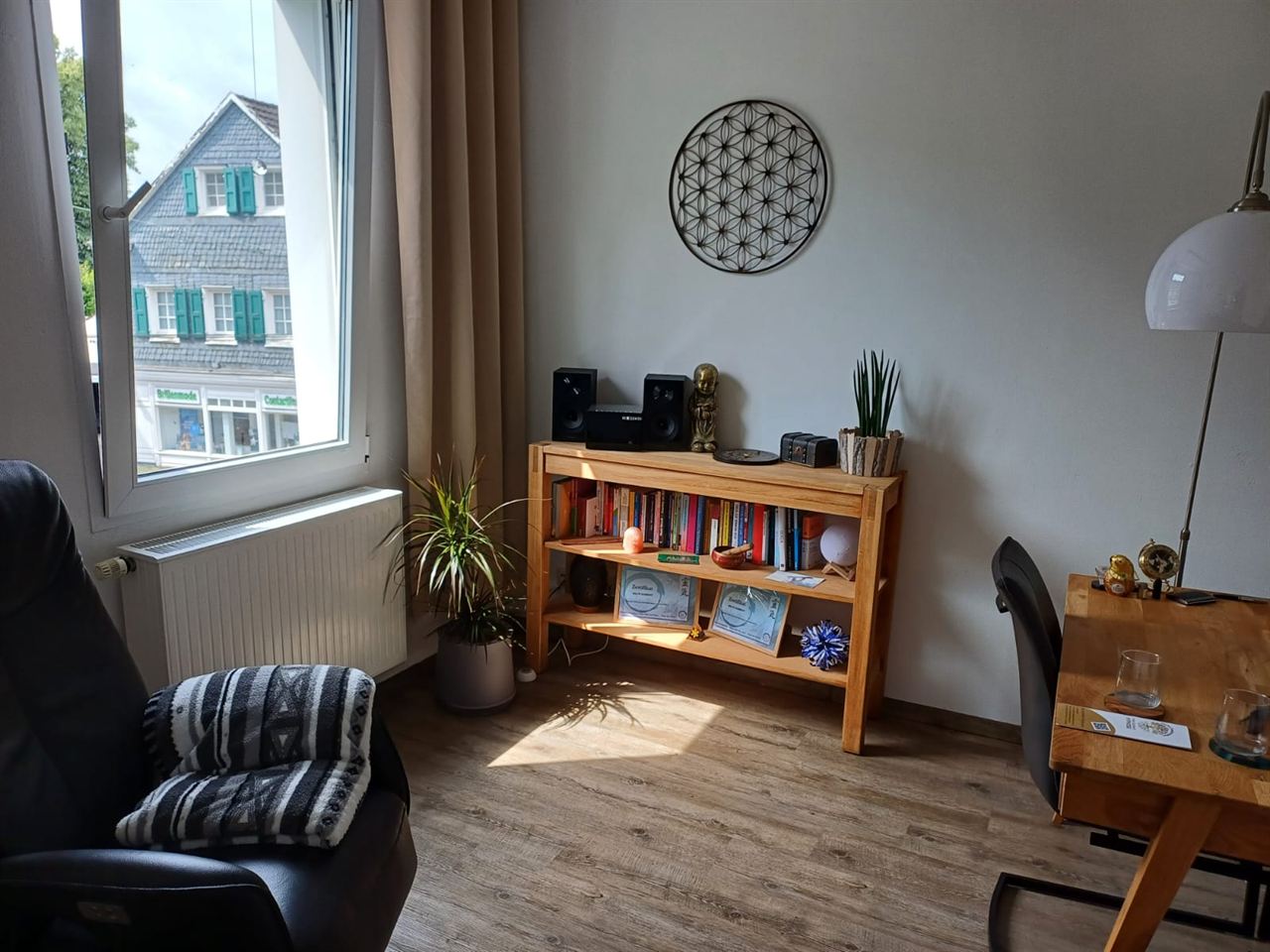 Coachingraum in Solingen mit Bücherregal, Blume des Lebens an der Wand und Blick auf ein Fachwerkhaus