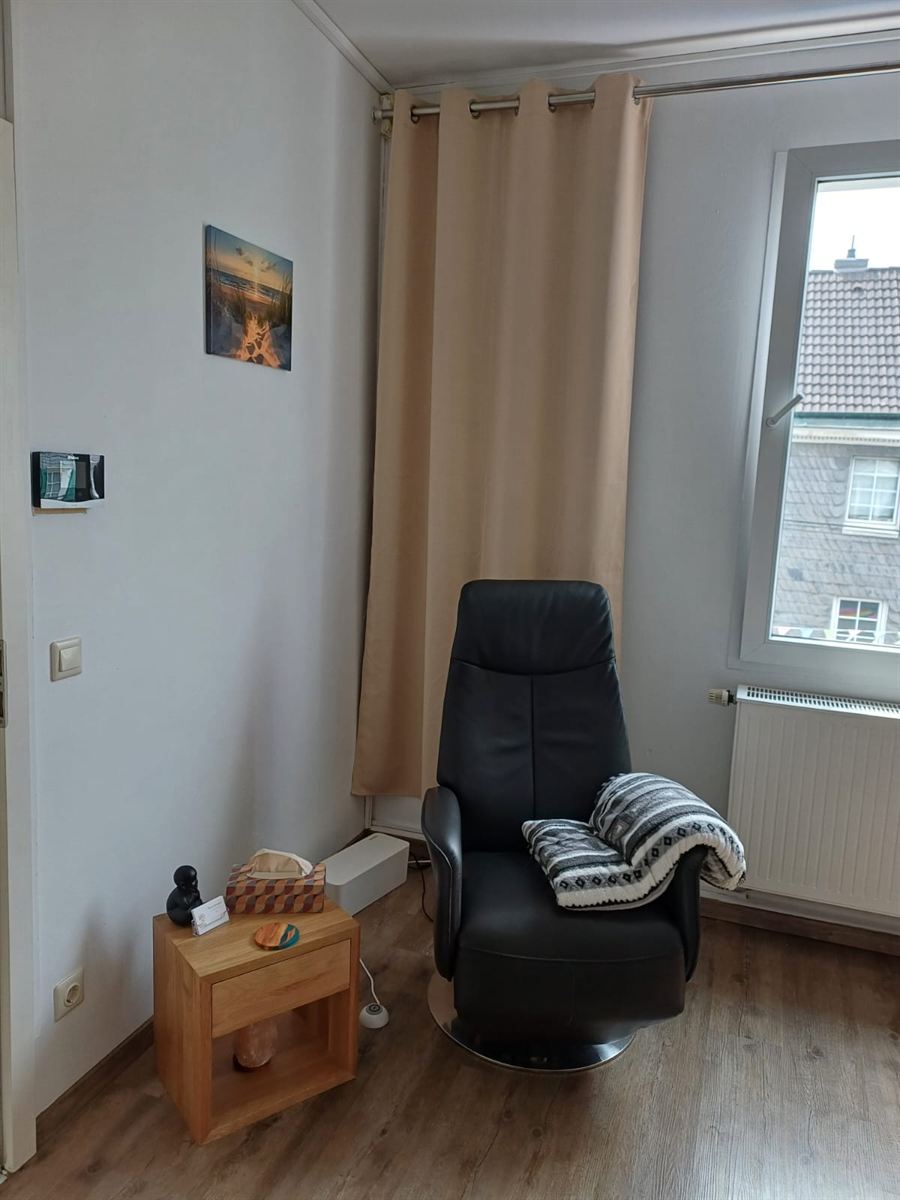 Schwarzer Entspannungssessel mit Decke, daneben ein Beistelltisch mit Salzlampe