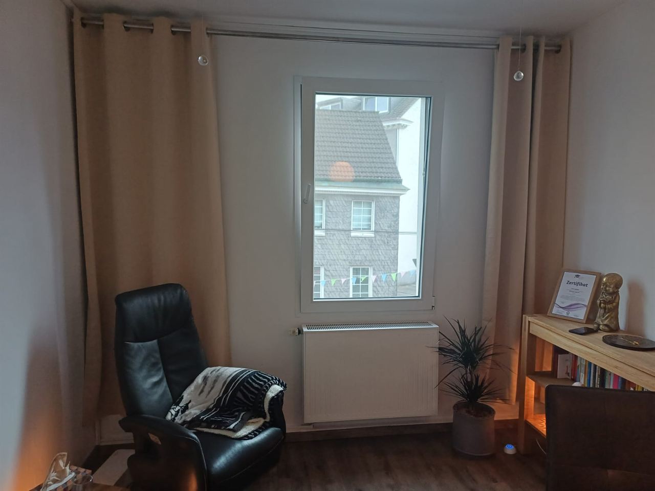 Ruheecke des Coachingraums mit Sessel, Fenster und indirekt beleuchtetem Regal